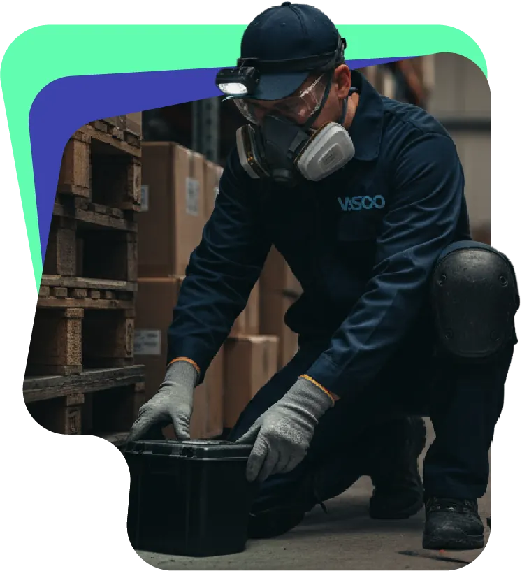 Técnico inspeccionando una estación de control de roedores junto a pallets